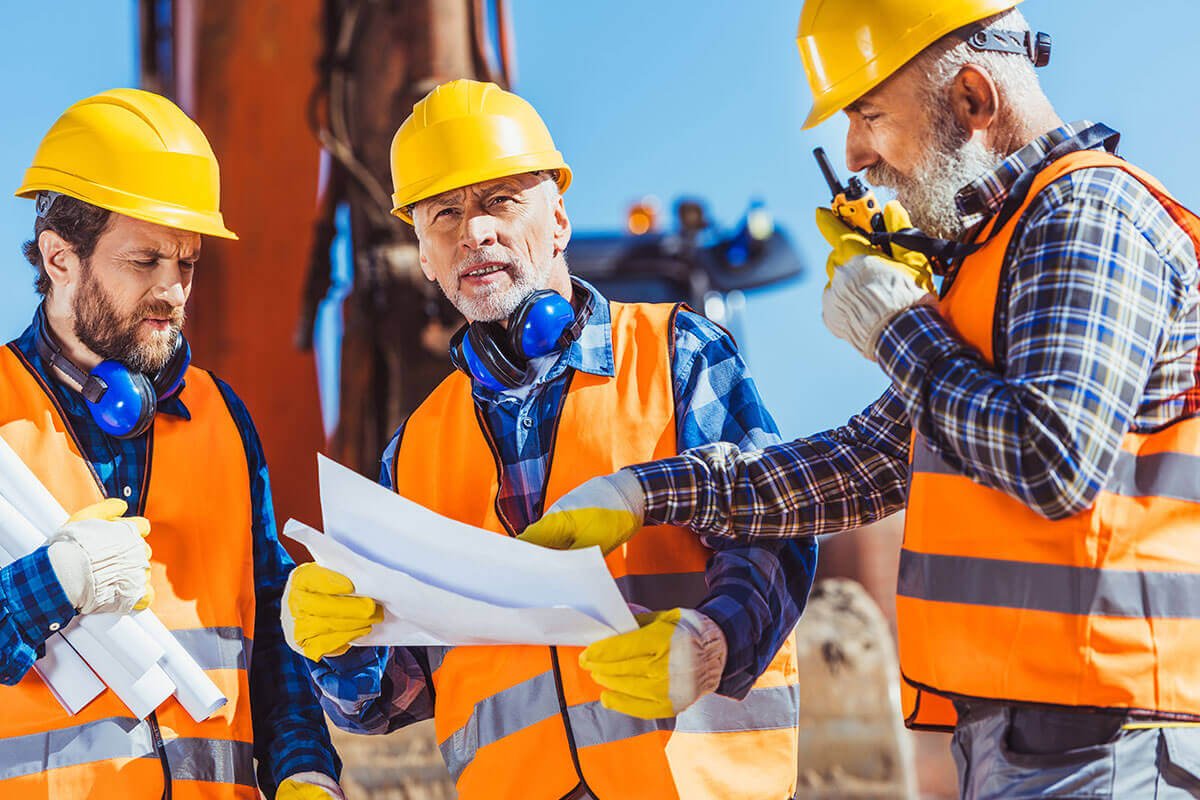 three-workers-examining-building-plans-and-talking.jpg